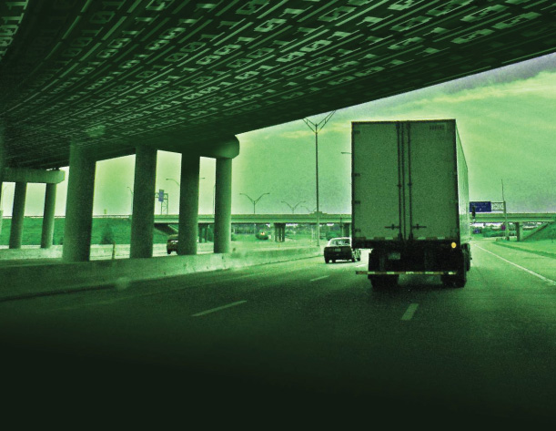 Semi truck driving on highway under bridge