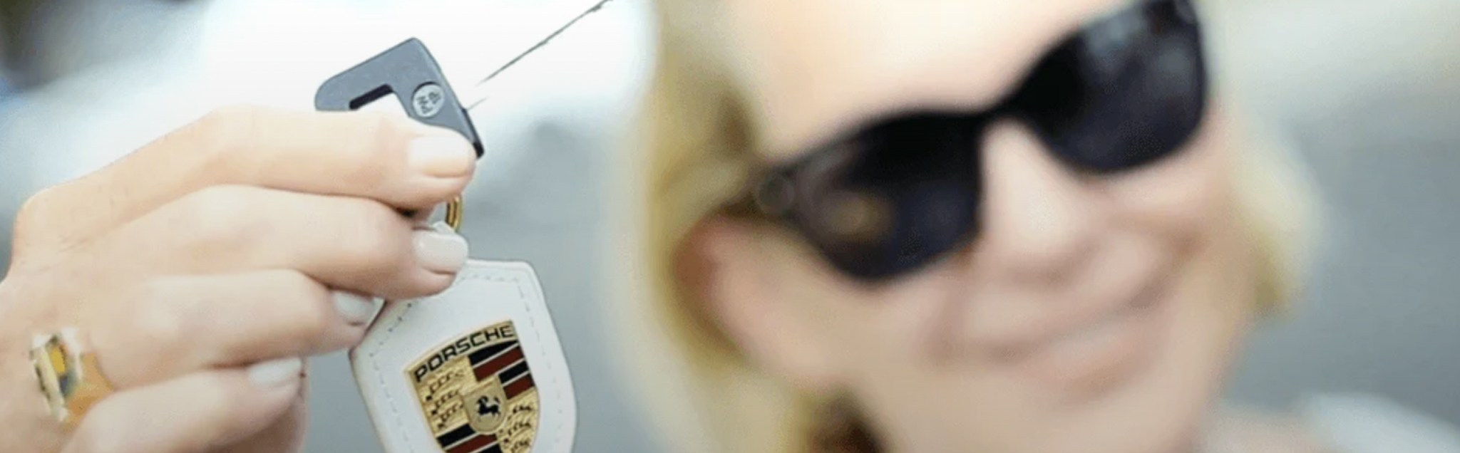 Women holding a key with a Porsche logo key chain