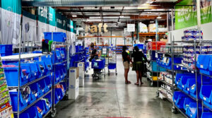 looking down an aisle of a warehouse with blue bins on either side